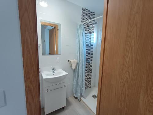 a white bathroom with a sink and a shower at Pensíon Lucia in Casinos