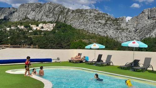 a group of people in a swimming pool with a mountain at ZEcamping 2 avec piscine restaurant vue sur le village de Saint Auban in Briançonnet