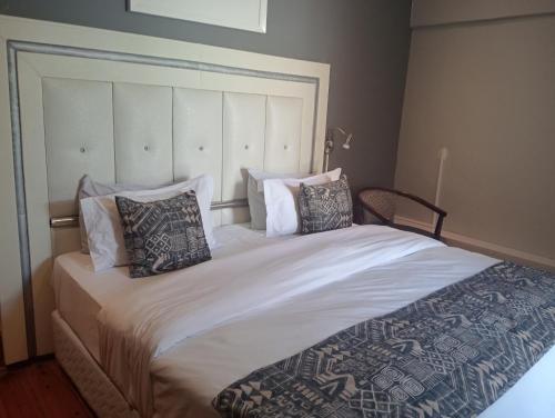 a bedroom with a large white bed with pillows at Steps On Cape Guest House in Gqeberha
