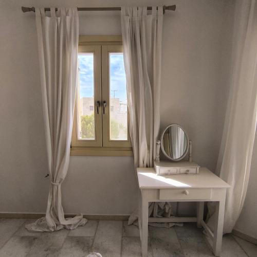 a dressing table with a mirror and a window at Theros Casa Logaras in Piso Livadi