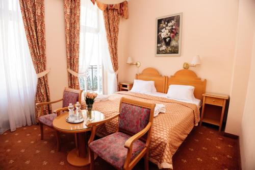 a hotel room with a bed and a table and chairs at Hotel Pavlov in Karlovy Vary