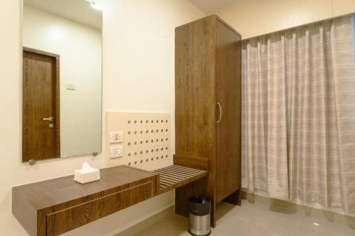 a bathroom with a mirror and a wooden cabinet at Hotel Sitara Residency in Navi Mumbai