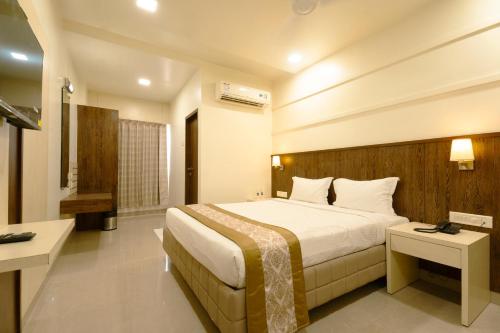 a hotel room with a bed and two tables at Hotel Sitara Residency in Navi Mumbai