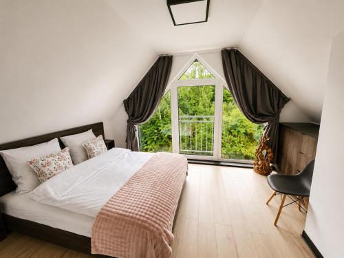 a bedroom with a bed and a large window at VeloDomki Żywiec - domki nad Jeziorem Żywieckim in Żywiec
