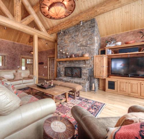 a living room with a stone fireplace and a tv at Lone View Lodge in Big Sky Mountain Village