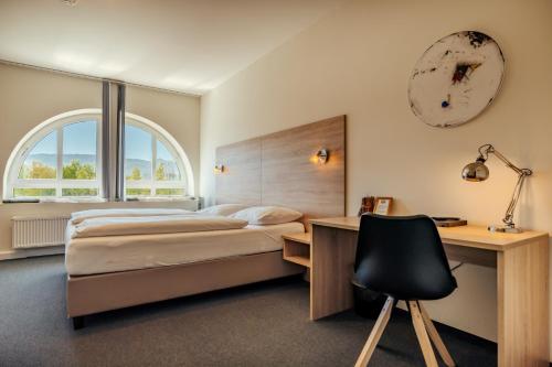 a bedroom with a bed and a desk and a clock at Das Karl August in Fohnsdorf
