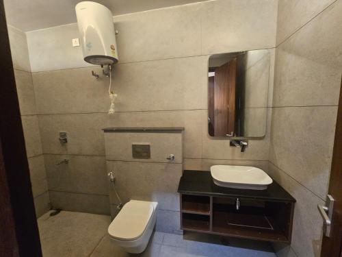 a bathroom with a toilet and a sink and a mirror at Hotel Gangotri Suites in Haridwār