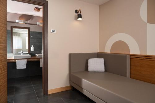 a bathroom with a bench with a sink and a mirror at Hotel Europa Belluno in Belluno