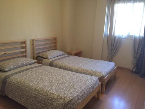 2 camas individuales en una habitación con ventana en Apartamentos EOS, en Buzanada