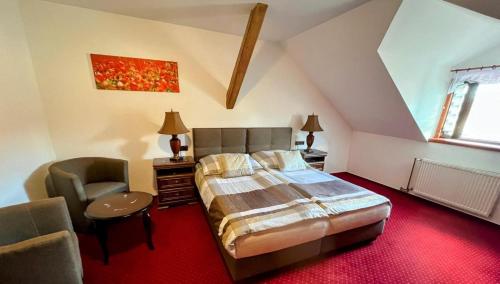 ein Schlafzimmer mit Bett und Stuhl auf dem Dachboden in der Unterkunft Hotel Fogl in Nová Bystřice