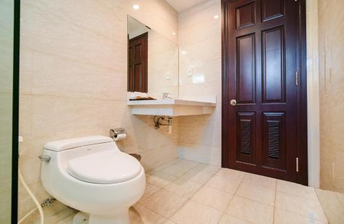 a bathroom with a toilet and a sink and a door at Galliot Hotel Nha Trang in Nha Trang