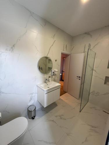 a white bathroom with a sink and a mirror at Hotel Omw Vore in Vorë