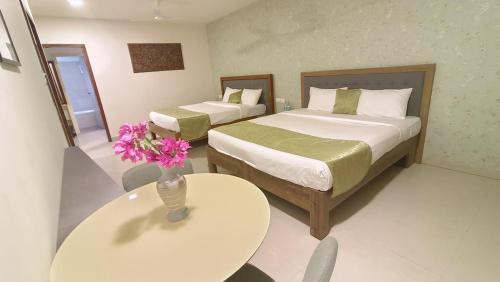 a hotel room with two beds and a table with flowers at Amazinn Hotel in Lonavala