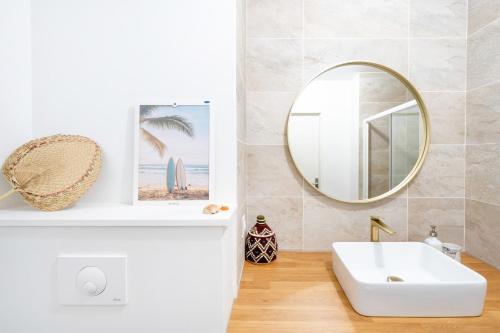a bathroom with a white sink and a mirror at Appartement proche du port in Capbreton
