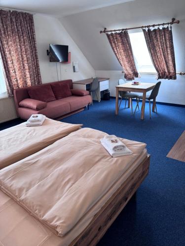 a bedroom with a bed and a table and a couch at Hotel Kelkheimer Hof in Kelkheim
