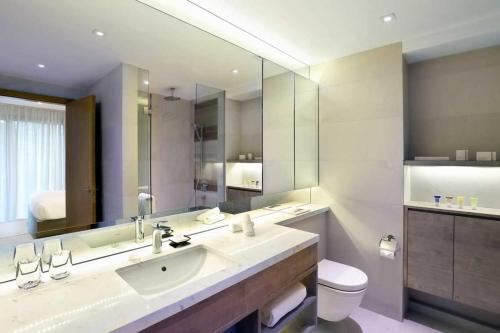 a bathroom with a sink and a toilet and a mirror at Oakwood Studios Singapore in Singapore