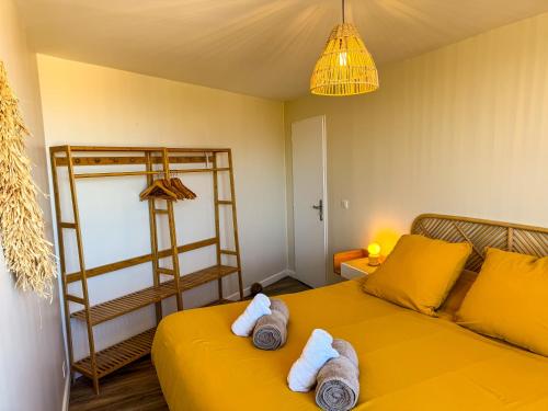 a bedroom with a yellow bed with towels on it at La Tour Myra in Valras-Plage