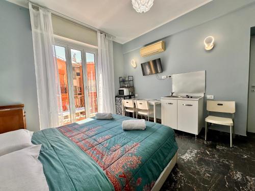 a bedroom with a bed and a desk and a kitchen at La Fenice - Studio Flat in Finale Ligure