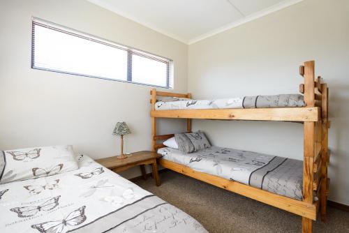 a bedroom with two bunk beds and a window at Albatross Beach Guest House in Jeffreys Bay