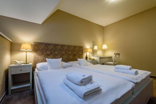 a bedroom with a large white bed with towels on it at Penzión Central Park in Žilina