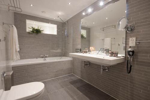 een badkamer met een wastafel, een bad en een toilet bij Grand Canal Boutique Hotel in Amsterdam