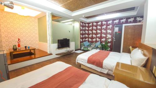 a hotel room with two beds and a television at 青禾溫泉家民宿 in Jiaoxi