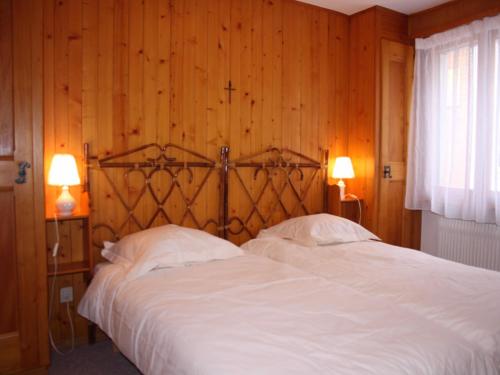 2 Betten in einem Schlafzimmer mit Holzwänden und 2 Lampen in der Unterkunft Pietra Serena 021 in Verbier