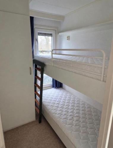 two bunk beds in a room with a window at Prachtig chalet in Koudum