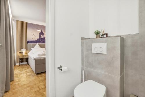 a bathroom with a toilet and a bedroom at Colleen Apartments Wesertal in Porta Westfalica