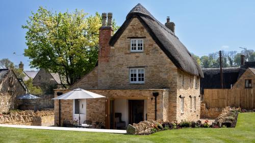 an old stone house with an umbrella in the yard at Garden Cottage in Chipping Campden