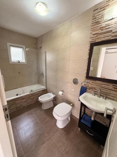 a bathroom with a toilet and a sink and a tub at Complejo del jaguel Cabaña Antuan Aires del bosque in Santa Teresita