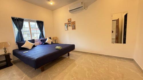 a large blue bed in a room with a window at Riverside By GikiJoy in Agarvado