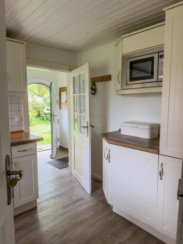 a kitchen with white cabinets and a microwave at Mühlenhof, Keitum auf Sylt in Sylt