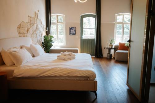 ein Schlafzimmer mit einem Bett mit weißen Laken und Fenstern in der Unterkunft Mila - Boutique Hotel in Haifa