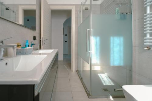 a white bathroom with two sinks and a shower at Villa Bianca in Perledo