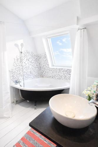 a white bathroom with a tub and a sink at La Maison Créative in La Madeleine