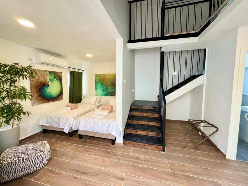 a bedroom with two beds and a staircase at אצל מאיה ואבשי Maya and Avshi in Neʼot HaKikar