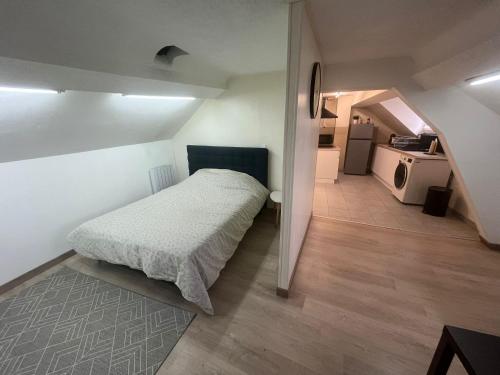 a small bedroom with a bed and a kitchen at Spacieux studio in Montlhéry