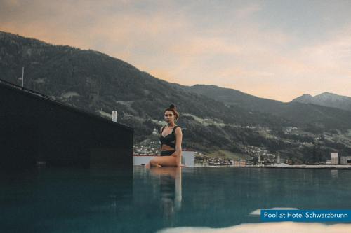 a woman sitting on the edge of a swimming pool at Villa Schwarzbrunn in Stans