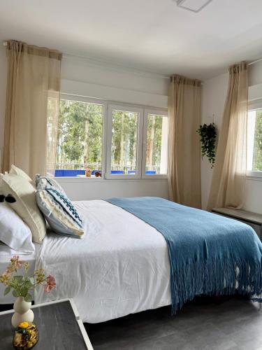 a bedroom with a bed with a blue blanket and windows at el AS del Puntal in Villaviciosa