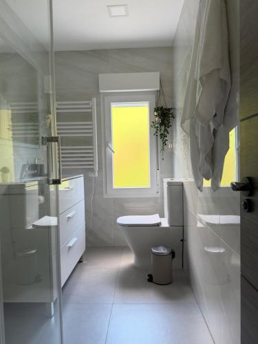a white bathroom with a toilet and a window at el AS del Puntal in Villaviciosa