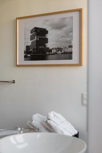 a picture hanging on a wall above a sink at A Place Antwerp - Boutique Hotel Emile in Antwerp