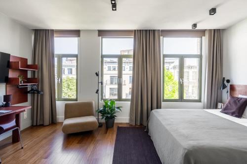 a bedroom with a bed and a desk and windows at A Place Antwerp - Boutique Hotel Emile in Antwerp
