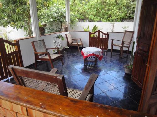 un porche acristalado con sillas y una mesa en La Breeze, en Hikkaduwa