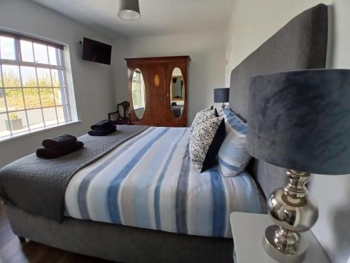 a bedroom with a bed with a lamp and a window at The Coast House in Kilmore