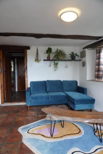 a living room with a blue couch and a table at Dairy Cottage in Hennock