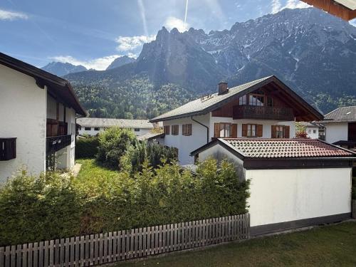 a house with a fence and mountains in the background at Alpensegler in Mittenwald