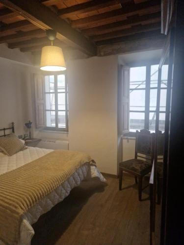 a bedroom with a bed and a chair and windows at DuomoHome1 in Pietrasanta