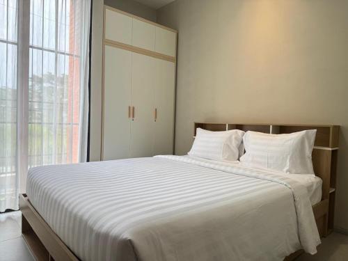 a bedroom with a large bed with white sheets and a window at Villa Grand Metro in Batu