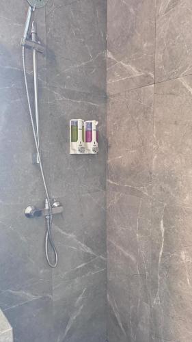 a shower in a bathroom with a stone wall at Villa Grand Metro in Batu